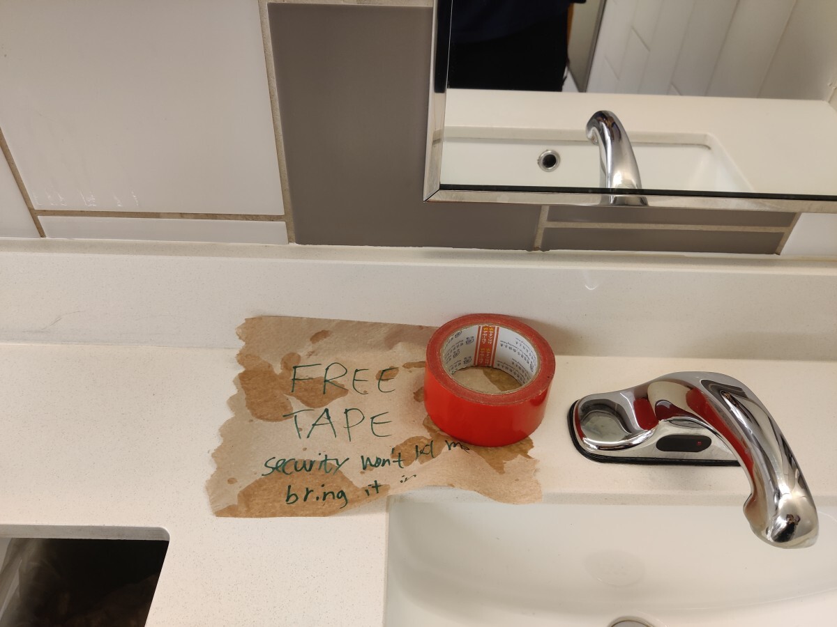 Red tape on a sink. A paper towel under it reads "Free Tape — security
won't let me bring it in"