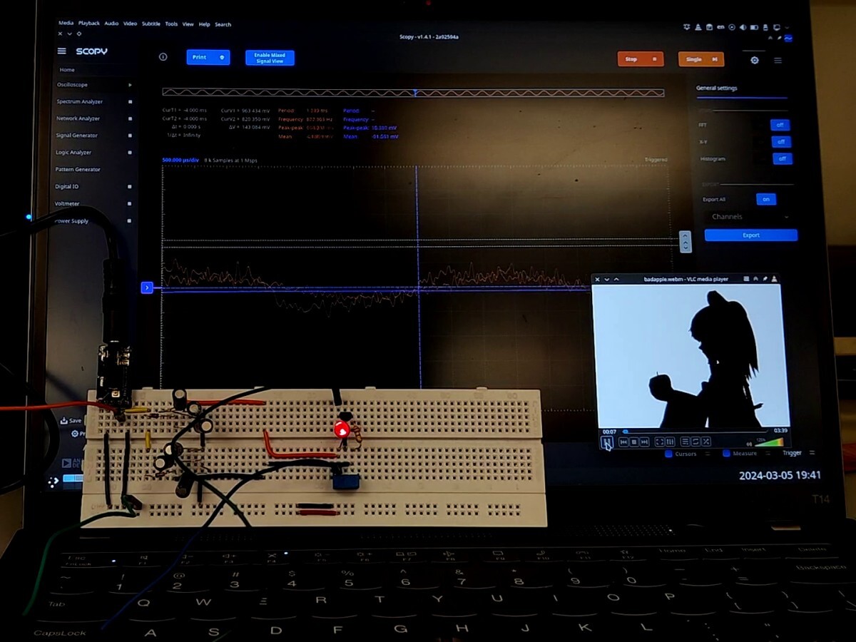 Bad Apple playing next to an oscilloscope waveform. An LED lights up on
a breadboard circuit